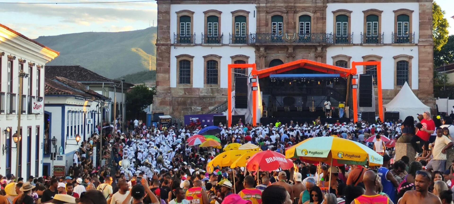 Foto – Tarde de carnaval com palco e foliões na Praça Tirandentes / jornal-voz-ativa-ouro-preto-mg-minas-gerais-op-materia-dia-de-carnaval-praca-tiradentes-ouro-preto-mg-foto-tino-ansaloni Praça Tiradentes em tarde de Carnaval com palco e foliões / Crédito - Tino Ansaloni